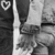 Black-and-white image of hands clasped with text about God and spaces between fingers, featuring a heart symbol in the top-left corner.