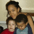 Three people pose closely together in a pixelated static image with one person standing behind two seated individuals.
