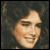Pixelated static image of a person's face with light skin tone and dark hair against a dark background, rendered in low-resolution 256x256 pixels.