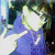 A person in a blue top with light-colored hair appears in a pixelated image with bright lighting and dark background elements.