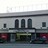 Pixelated static image of a building facade with three vertical dark shapes above a horizontal band and two smaller dark shapes on either side.