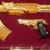 Golden gun with black grip on maroon background, animated with horizontal motion blur effect.