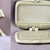 A static pixelated image of a light-colored rectangular object with rounded corners and dark trim, positioned against a muted purple background.