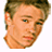 Pixelated portrait of a person with light brown hair and blue eyes, wearing a white shirt against a plain background.