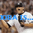 Pixelated cartoon figure in white uniform with black cap and tie, holding brown object against blurred background with blue text overlay.