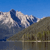 Pixelated landscape with blue sky, white clouds, brown terrain, and water reflection.