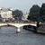 Pixelated static image showing a light-colored vehicle on a bridge with dark trees and water in the background.