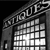 Black-and-white pixelated image of a building with a grid-patterned window and a curved roofline, featuring partial text above the window.