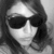 Black-and-white pixelated image of a person with dark hair wearing large sunglasses, showing only the upper face and shoulders against a light background.