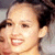 Pixelated close-up of a person's face with dark hair, showing a smiling expression and visible teeth.