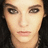Pixelated close-up of a person's face with light skin, dark eyes, and brown eyebrows against a black background.