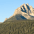 Pixelated landscape showing a mountain with snow-capped peaks under a clear blue sky, with a grassy foreground.
