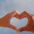 Four heart-shaped compositions: hands forming a heart, sand drawing, silhouettes, and light reflection on water.