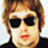 Pixelated static icon of a person with short brown hair, dark sunglasses, and red lips against a light background.