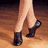 A pixelated image of a person's legs in black ankle boots on a wooden floor, next to a colorful abstract pattern.