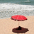 Pixelated beach scene with red umbrella on sand, ocean waves in background.