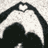 A pixelated black and white icon featuring a stylized heart shape with curved edges, set against a light gray background.