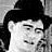 Black-and-white pixelated image of a person with dark hair and a dark hat, face partially visible in grayscale tones.