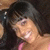 Pixelated close-up of a person with dark hair and light skin, wearing pink clothing against a dark background.