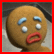 Pixelated gingerbread man face with four eyes, blue eyebrows, red lips, and a brown body against gray background.