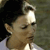 Pixelated close-up of a person's face with closed eyes, dark hair, and light skin, wearing a white top against a muted green background.