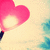 A pink heart-shaped icon with a glowing center and dark stem, set against a light background with blue cloud-like shapes.