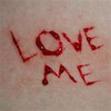 Red handwritten text reading LOVE ME on a light beige background with visible texture.