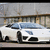 White sports car with blue-tinted windows positioned on a road, viewed from a low angle against a blurred background.