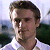 Pixelated static image of a person's face and upper torso against a blurred background with light blue, white, and dark green tones.