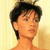 Pixelated close-up of a person with short dark hair against a light yellow background, showing partial facial features and neck.