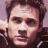 A 48x48 pixel buddy icon split into two vertical sections: a left-side portrait of a person with brown hair and dark clothing, and a right-side green background with bright green text reading "OriginalIcons.com" in stylized font.