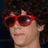 A person with curly dark hair and red sunglasses appears in a of six , each showing different blue letter overlays