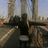 Pixelated static image shows a dark figure with outstretched arms against industrial smokestacks under a pale sky.