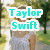Pixelated image of a woman in a light blue dress standing outdoors with trees and grass, overlaid with cyan text reading "Taylor Swift".