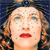 Pixelated close-up of a person's face with light skin, brown eyes, and red lips, set against a dark blue background with scattered light-colored pixels.