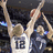 Two pixelated figures in white jerseys with dark numbers stand side-by-side against a dark background, one holding an object above their head.