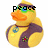 Pixelated yellow rubber duck with orange beak, wearing dark purple vest with red flower, blue peace sign necklace, and green-tinted glasses, with text above its head.