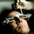 A person with light skin and brown hair lies on their back while a hand pours liquid from a bottle onto their forehead.