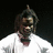 A pixelated image of a person with long hair wearing a white shirt and dark bow tie, alongside a small black-and-white icon resembling stacked blocks.