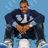 Pixelated image of a person in a dark jacket with light accents, white shirt, and white pants against a light blue background.