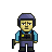 Pixelated character with yellow skin, purple helmet, blue shirt, dark vest with yellow square and black cross symbol, holding a green object.