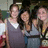 Three people stand closely together in a group pose, with the central figure slightly forward, all facing the camera.
