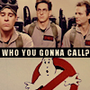 Three men in beige jumpsuits with red name tags stand side-by-side above a red and white ghost logo and text reading "WHO YOU GONNA CALL?".