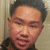 Pixelated close-up of a person with short dark hair, light skin tone, and closed eyes against a neutral background.