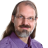 Static pixelated image of a person with long brown hair, glasses, and a purple shirt against a gray background.