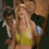 Britney Spears in a yellow dress with blue earrings, performing against a dark background.