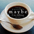 A pixelated image of a white cup filled with dark liquid, featuring visible text on the surface and a spoon resting inside.