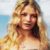 Pixelated image of a person with long blonde hair, light skin tone, and closed eyes against a blue sky background.