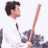 Pixelated image of a person with dark hair wearing a white shirt, holding a long brown object resembling a bat or stick, with a blurred background.