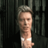 Animated sequence of a person in a black suit against dark metal bars, transitioning from open mouth to finger-to-lips gesture with blue text overlay.